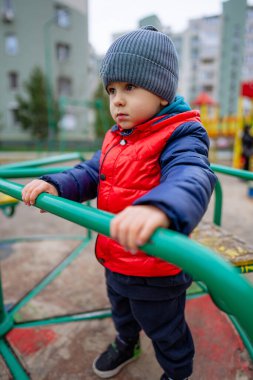 Canlı Kırmızı Ceketli Maceracı Küçük Çocuk ve Rahat Gri Şapkalı. Kırmızı ceketli ve gri şapkalı küçük bir çocuk.