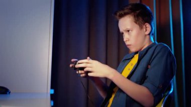 Evde oyun oynayan bir çocuğun yan görüntüsü. Ciddi bir genç, joystick kullanarak video oyunu oynar ve kazandığında mutlu olur..