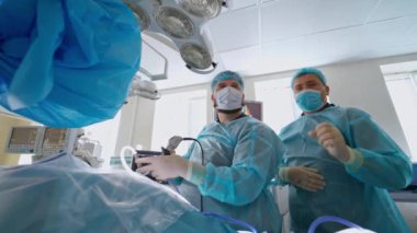 Bir hastaya ameliyat sırasında uzman cerrahlar. Tıp üniformalı doktorlar modern hastanedeki bir hastayı ameliyat ediyorlar..