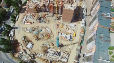 Şehirdeki yolun yakınında yeni bir mimari inşa ediliyor. Şehir merkezindeki modern bir bölgenin şantiyesine yukarıdan bak. Hava görünümü.