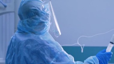Şırıngayla çalışan koruyucu üniformalı hemşire. Klinikte doktor asistanı ve yüz maskesi var. Covid-19 konsepti.