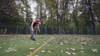 Güçlü bir adam spor alanında şınav çekiyor. Spor yaparken kaslı vücutlu yakışıklı bir sporcu. Yavaş çekim.