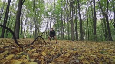 Sporcu sonbahar ormanında savaş halatlarıyla dalgalar yapıyor. Siyah spor giyim giymiş atletik bir adam halatlarla antrenman yapıyor ve gidiyor. Yavaş çekim.