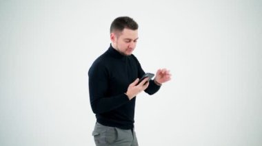 Akıllı telefondan konuşan profesyonel yaratıcı adam. Beyaz stüdyo arka planında izole edilmiş cep telefonu kullanan siyah kazaklı yakışıklı bir adam..