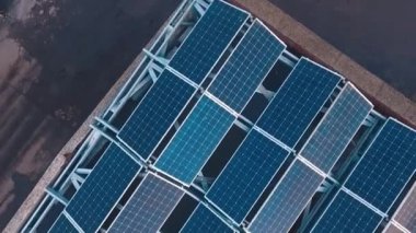 Çatıdaki yenilikçi güneş paneli koleksiyonlarının en üst görüntüsü. Güneşten temiz ekolojik enerji almak için mavi fotovoltaik paneller. Hareket kamerası geri. Drone görünümü.
