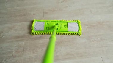 Yeni yeşil paspas parke zemininde hareket ediyor. Evi mikrofiber paspasla temizliyorum. Ev işleri işte. Yakın plan..