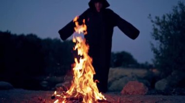 Siyah figürlü karanlık arka planda ateş alevi. Akşamları ateşin yanında ölüm silueti. Cadılar Bayramı 'nda korkunç bir atmosfer.