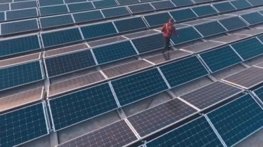 İnsan modern güneş çiftliğinde yürüyor. Yenilikçi fotovoltaik güneş panelleri güneş enerjisi topluyor. Sürdürülebilir temiz enerji.