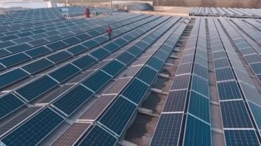 Binanın tepesindeki modern güneş enerjisi santrali. İnsan güneş pilleri arasında yürüyor. Güneşten gelen alternatif temiz enerji kaynağı. Hava görünümü.