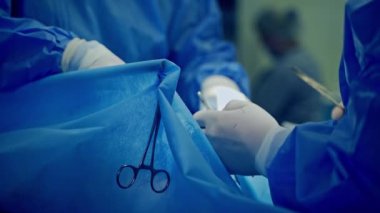 Uzmanlar tarafından cerrahi işlem. Ameliyat sırasında cerrahi aletlerle çalışan beyaz steril eldivenli doktorların elleri. Yakın plan..