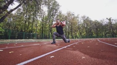 Stadyumda sporcu eğitimi. Sırtında 10 kg ağırlığında güçlü bir sporcu ve dışarıda antrenman yapıyor. Yavaş çekim.