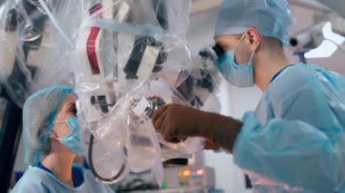 Klinikte beyin cerrahisi. Profesyonel doktorlar yeni elektronik ameliyat mikroskobuyla ameliyat yapıyorlar. Cerrahlar modern ekipman kullanır. Sağlık hizmeti kavramı.