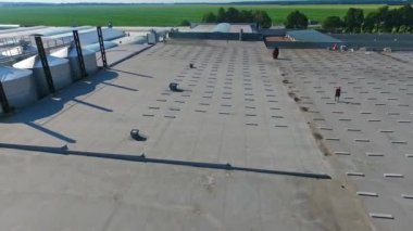 Düz çatıda güneş çiftliği inşa etmek. Geleceğin alternatif enerji santralinin inşaat sahasının üzerinde uçuyor. Hava görünümü.