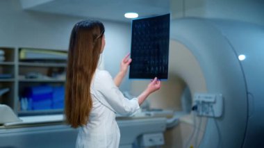 Kadın doktor ve bir hemşire röntgen fotoğrafına bakıyor. İki uzman, klinikteki modern tıbbi ekipmanların arkaplanlarını analiz ediyor..