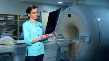 Kadın doktor röntgen fotoğrafını inceliyor. Modern klinikte durup radyoloji taramasına bakan güzel bir doktor. Hastanedeki gelişmiş ekipmanlar..