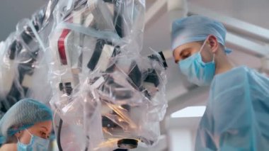 Cerrah ameliyat sırasında mikroskop kullanır. Tıp uzmanı ve maskeli bir hemşire modern ekipman geçmişi üzerinde bir ameliyat yapıyorlar. Nöroşirürji konsepti.