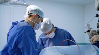Bir grup doktor bir hastaya ameliyat yapıyor. Ameliyathanede çalışan tıp üniformalı ve maskeli cerrahlar. Nöroşirürji.