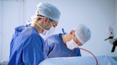 Bir grup doktor bir hastaya ameliyat yapıyor. Ameliyathanede çalışan tıp üniformalı ve maskeli cerrahlar. Nöroşirürji.