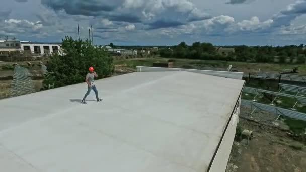 屋顶上戴橙色头盔的技师工人们在一座新的太阳能农场的背景下 在一座工业大楼的平顶上工作 空中景观 — 图库视频影像