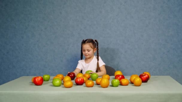 快乐的小女孩拿着成熟的水果在桌上玩耍 快乐的孩子用新鲜的有机苹果建造了一座塔 桌上放着富含维生素的健康水果 — 图库视频影像