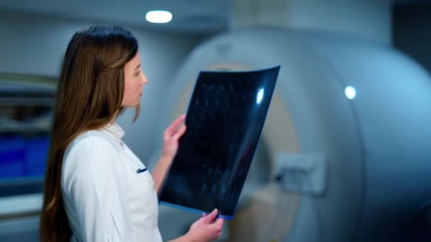 Νεαρός Ακτινολόγος Γιατρός Εξετάζει Μια Ακτινογραφία Στην Κλινική Γυναίκα Νοσοκόμος — Αρχείο Βίντεο