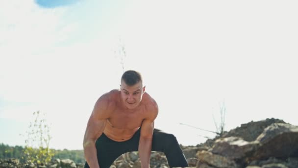 肌肉发达的男人 受过训练的身体用石头操练 强壮的健美运动员在大自然的背景下扔重石锻炼身体 — 图库视频影像