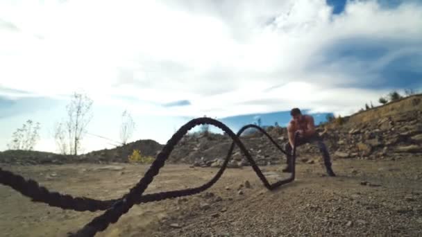 运动员在室外用战斗绳进行训练 强壮的运动员在自然界的岩石中 用战斗绳进行双波和交替运动 — 图库视频影像