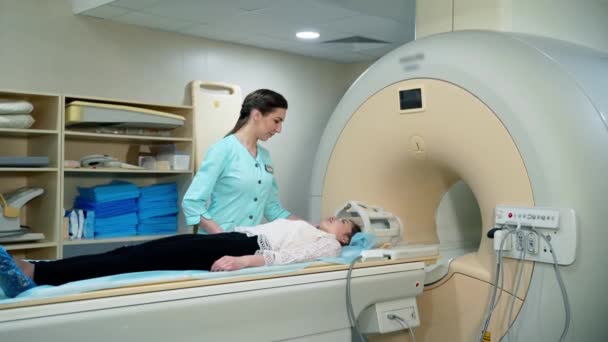病院の磁気共鳴イメージデバイス Mriマシンに横たわっている女性患者と医療従事者が手順をコントロールします 高度な医学 — ストック動画