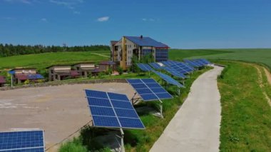 Doğada güneş panelleri olan bir bina. Yol boyunca mavi güneşli bataryalar. Fotovoltaik hücreler yaz aylarında güneş ışığında ekolojik enerji üretirler..