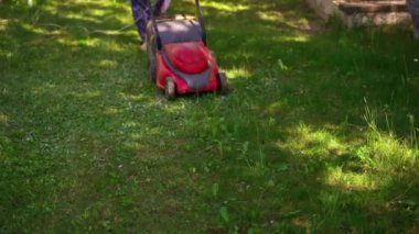 Bahçıvanlık. Birisi elektrikli çim biçme makinesiyle çimleri biçiyor. Çimleri biçiyorum. Bahçeyi düzenliyorum..