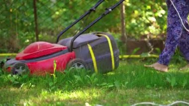 Bahçe malzemeleri. Elektrikli çim biçme makinesiyle çim biçen bir işçi. Çim biçme makinesi çalışıyor..