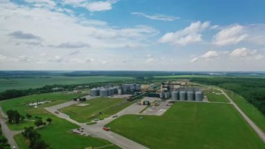 Doğadaki fabrika üretimi. Tarım tahıl depolama tankı. Yeşil alanlar arasında büyük metal silolar var. Hava görünümü.
