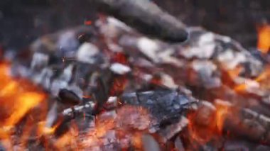 Ateşin içinde yanmış kütükler. Detaylı alev parıltıları. Şenlik ateşi dilleri. Parlak kıvılcımlı turuncu ateş. Parlak alevler içindeki odun Yakın plan..