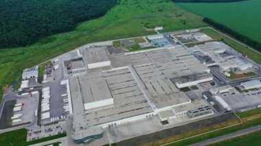 Sanayi kompleksi. Üretim binalarının çatılarından manzarayı izle. Yeşil alanda büyük bir fabrika. İHA iniyor.