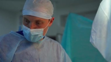 Tıbbi maskeli ve şapkalı bir doktor. Hastanedeki tıp uzmanlarının ameliyat prosedürü. Profesyonel cerrahlar ameliyat yapar. Sağlık hizmetleri kavramı.