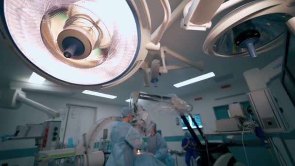 病院での神経外科的プロセス オペレーティング シアターの現代医療機器 顕微鏡を通して手術を行う医療チーム — ストック動画