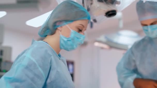 医生和一个护士在诊所 在医院进行神经外科手术的戴口罩的专科医生和女助手的脸 后续行动 — 图库视频影像