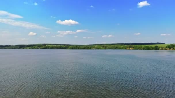 昼間のブルー川 青空の下の美しい水の背景 緑の自然の風景に囲まれた広い川 空からの眺め カメラの移動バック — ストック動画