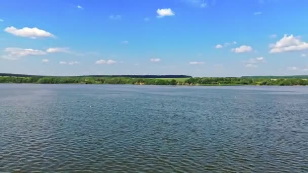 美しい川のパノラマビュー 明るい昼間の緑の自然の背景にある青い水 川を渡るフライト エアリアルビュー — ストック動画
