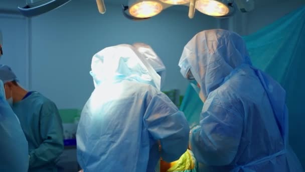 拥有医疗工具的专业外科医生 一组穿着安全服的医学专家在手术室为病人做手术 — 图库视频影像