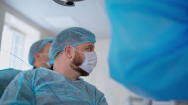 Tıbbi aletli bir cerrah. Tıp uzmanları, klinikteki modern ekipmanları kullanarak laparoskopik bir ameliyat gerçekleştiriyorlar. Bir doktorun yan görünüşü.