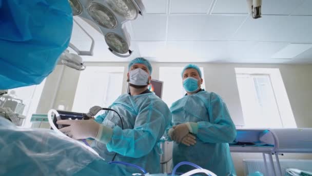 石を粉砕するための操作 青い制服とマスクの医療従事者は クリニックの近代的な手術室で手術を行います — ストック動画