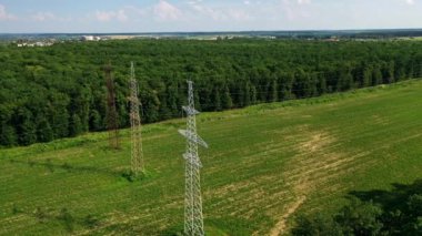 Yeşil Orman yakınlarındaki iletişim hatları. Alanda yüksek voltajlı elektrik hattı var. Güzel doğa arka planında elektrik için çelik sütunlar. Hava görünümü.