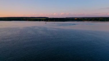 Tekne gün batımında denize açılacak. Endüstriyel fabrika arka planında akşam nehir manzarası. Sürat teknesi suda küçük bir tekne çekiyor. Yaz tatili. Hava görünümü.