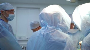 Doktorların takım çalışması. Mavi koruyucu giysili tıp çalışanları ameliyathanede bir operasyon düzenliyor. Operasyon salonu.