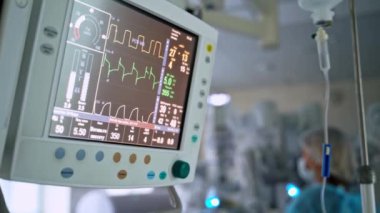 Ameliyathanede monitör var. Ameliyat sürecinin bulanık arka planındaki monitör ekranında hayati önem taşıyan hastaların tabelalarının şeması. Yakın plan..