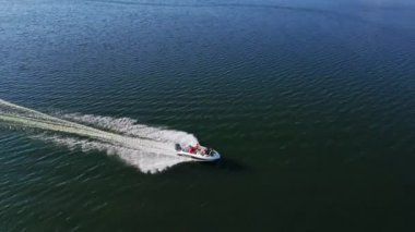 Mavi su yüzeyindeki sürat teknesi. Turistler denizde yüksek hızlı bir tekneyle seyahat ederler. Suyun üstünde giden tekneden sonra beyaz köpük. Hava görünümü.