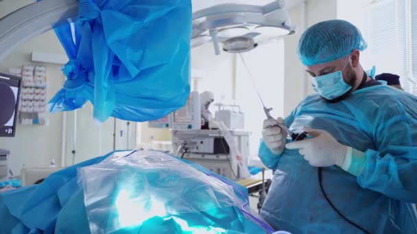 医生手中有外科设备 外科医生在手术前准备医疗工具 手术室里穿着蓝色制服工作的专业医生 — 图库视频影像