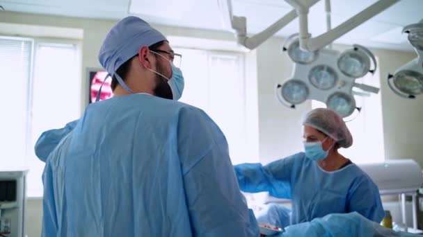 オペレーティングシアターでの外科的作業 オペレーションを実行し モニターの画面上のプロセスを観察する医師のチーム — ストック動画