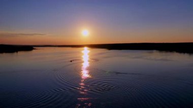 Doğada güzel bir gün batımı. Güneşli yol akşamları nehri yansıtır. Güneşin batışına karşı gölün muhteşem manzarası.